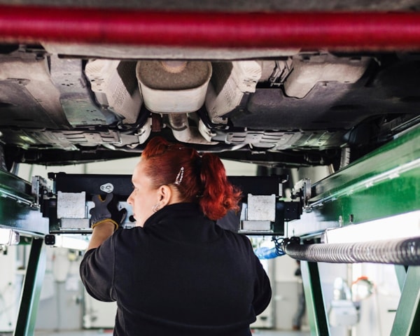 ung kvinnelig mekaniker inspiserer bilens understell